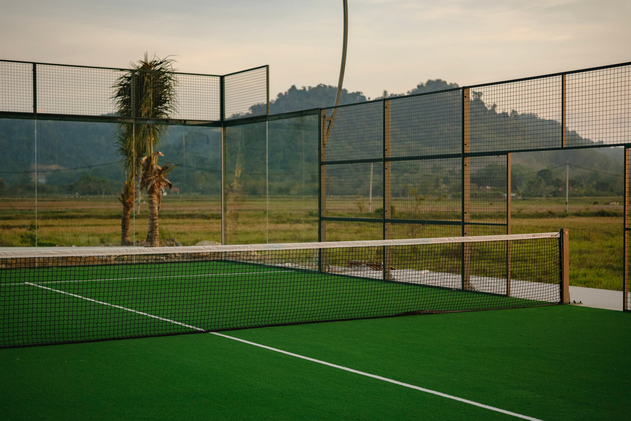 Outdoor padel court with glass walls looking onto open countryside