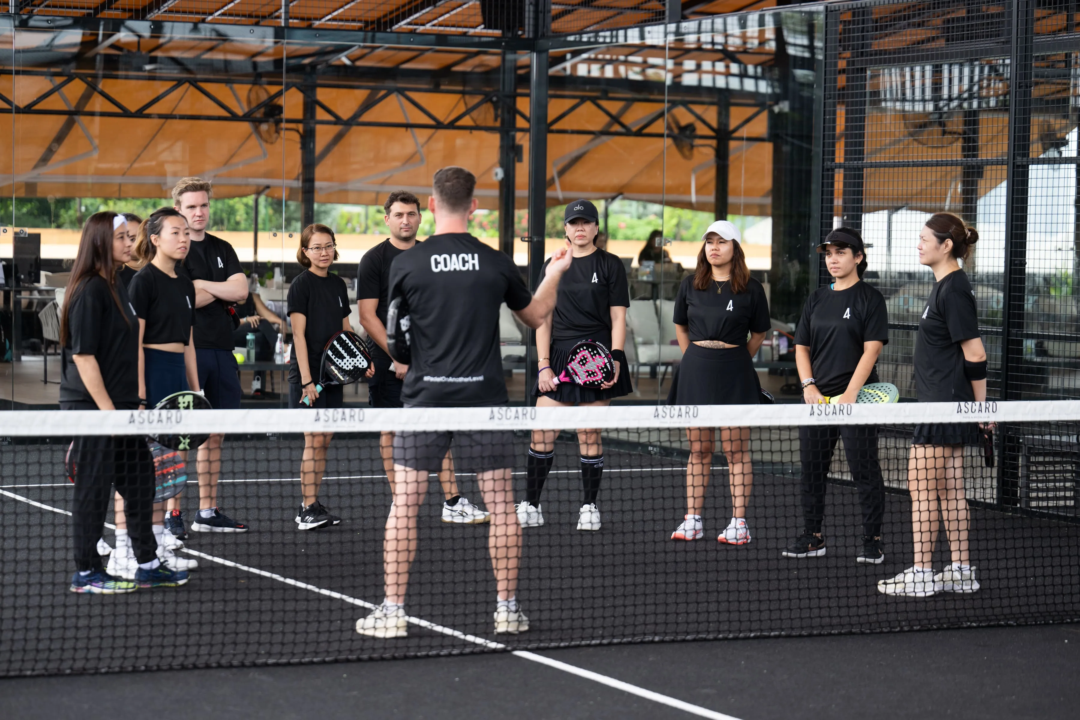 Coach addressing a group of padel players on court