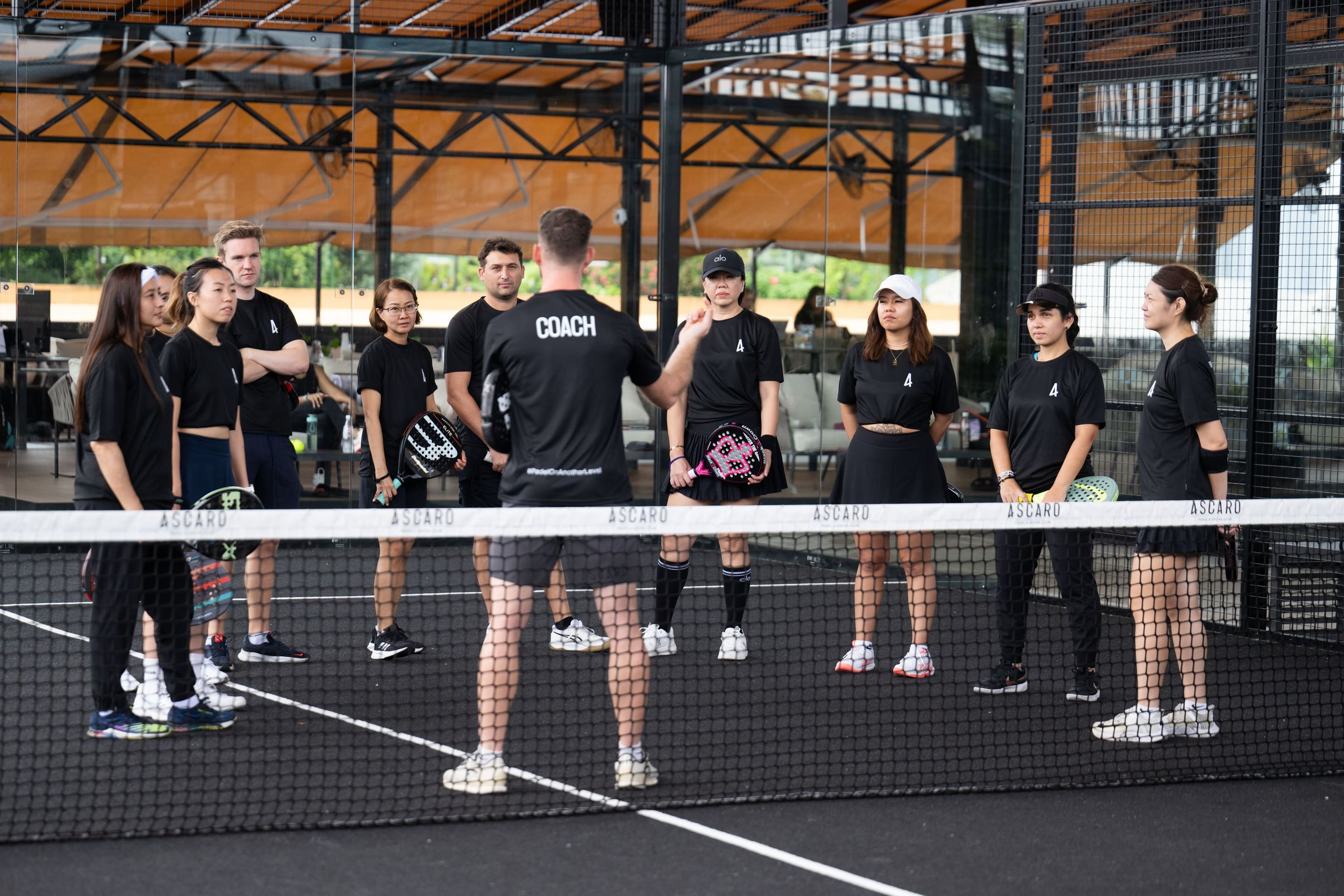 Coach addressing a group of padel players on court